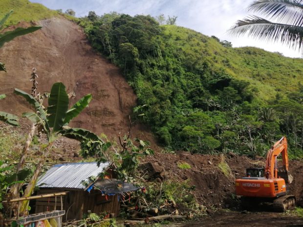 DIGGING FOR LIFE A backhoe is used in clearing landslide debris at Barangay San Luis inMalitbog, Bukidnon, to find four people still buried there on Tuesday. The body of a truck helper was earlier recovered from the site. —PHOTO COURTESY OF RMNDXCC