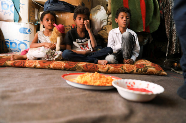 Children of Amal Hasan wait for lunch at their hut in Sanaa