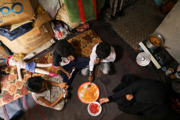 Amal Hasan and her children eat lunch at their hut in Sanaa