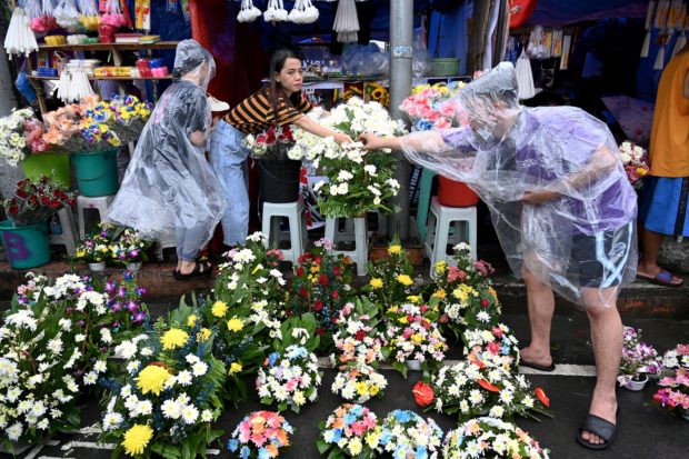Filipinos clutching flowers and umbrellas pour into cemeteries across the Catholic-majority Philippines on All Saints' Day, November 1, 2022
