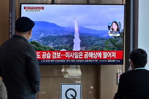 People watch a television screen showing a news broadcast with file footage of a North Korean missile test, at a railway station in Seoul on November 2, 2022. - South Korea on November 2 told residents on the island of Ulleungdo off its east coast to evacuate to bunkers after North Korea fired three short range ballistic missiles. (Photo by JUNG YEON-JE / AFP)