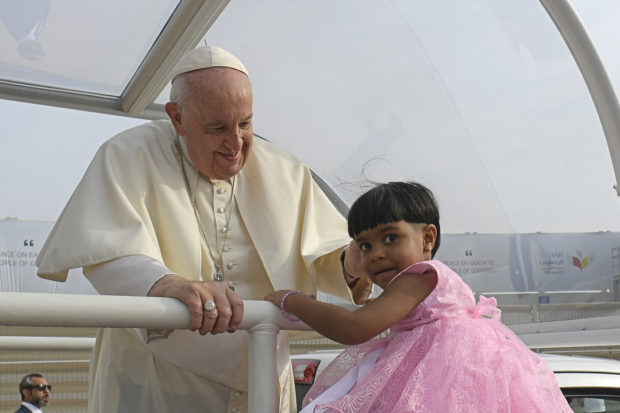 This handout photo released by the Vatican Media shows Pope Francis blessing a child as he arrives to celebrate mass at Bahrain National Stadium in Riffa, near the capital Manama, on November 5, 2022. - About 30,000 flag-waving worshippers joined an open-air mass held by Pope Francis in mainly Muslim Bahrain, the highlight of his outreach mission to the Gulf.