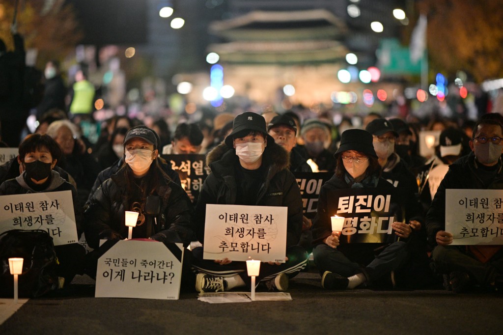 People take part in a candlelight vigil to commemorate the 156 people killed in the October 29 Halloween crowd crush, in Seoul on November 5, 2022. - Candlelight vigils and rallies were expected in South Korea on November 5 to commemorate the 156 people killed in a Halloween crowd crush, with public anger growing over one of the country's deadliest peacetime disasters. (Photo by ANTHONY WALLACE / AFP) korea vigil halloween victims