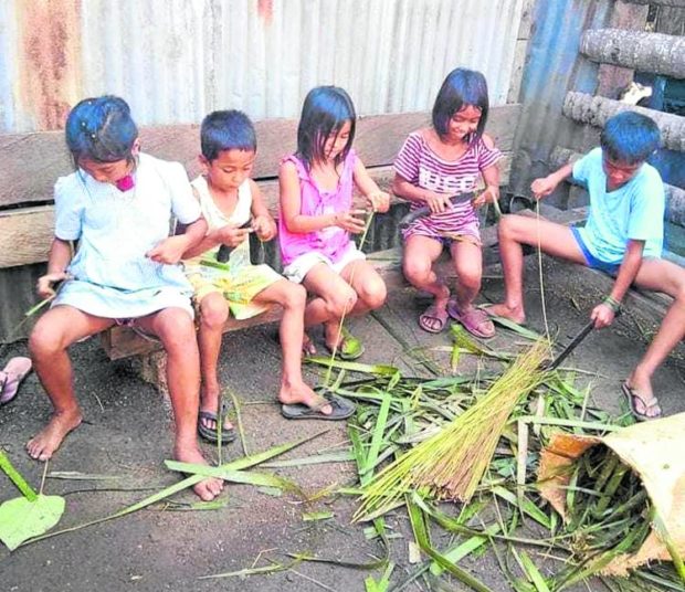 Children in Basilan chat with each other while making brooms that they exchanged for school supplies
