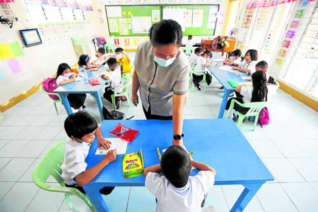 Photo of a public school teacher attending to her pupils for story: DepEd bares new perks for public school teachers