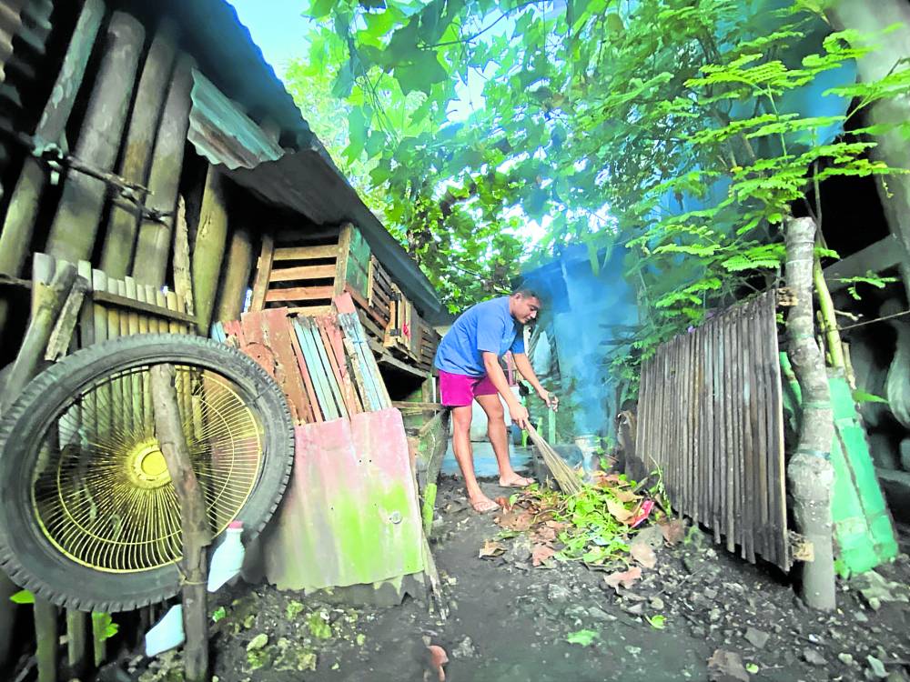 A resident of Barangay Booy in Tagbilaran City, Bohol, cleans the surroundings of his house on Friday to ensure that breeding spots of dengue-carrying mosquitoes are destroyed