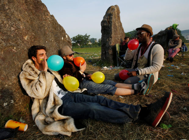 FILE PHOTO: Festival goers inhale laughing gas at sunrise at the stone circle on the second day of Glastonbury music festival at Worthy Farm in Somerset