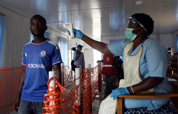 A health worker checks the temperature of a man as part of the ebola screening, in Mpondwe