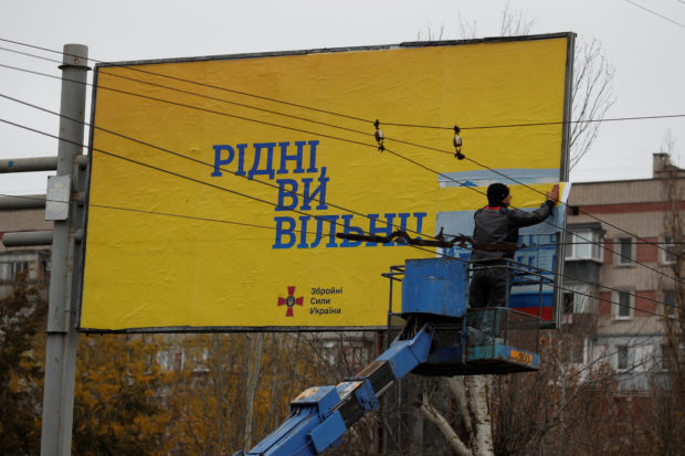 A municipality worker covers a pro-Russian billboard with a Ukrainian Armed Forces one reading: "Compatriots you are free!" after Russia's military retreat from Kherson, Ukraine November 22, 2022. REUTERS/Murad Sezer