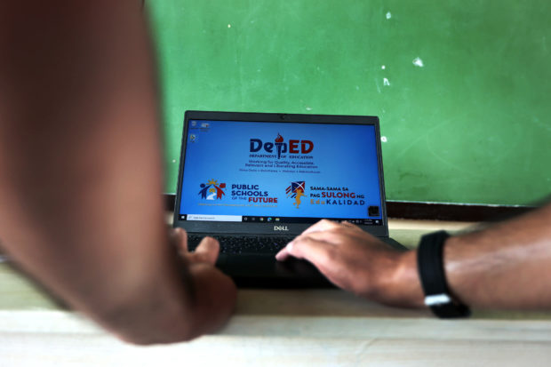 Open laptop with screen showing DepEd logo. STORY: ACT: Teachers still need DepEd laptops