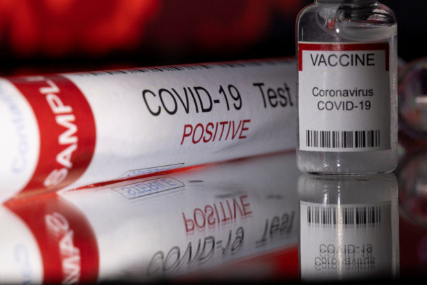 Stock photo of test tube printed with “COVID-19 Test Positive” and a vial of COVID-19 vaccine. STORY: Expert: 127% surge in COVID cases ‘not a concern’