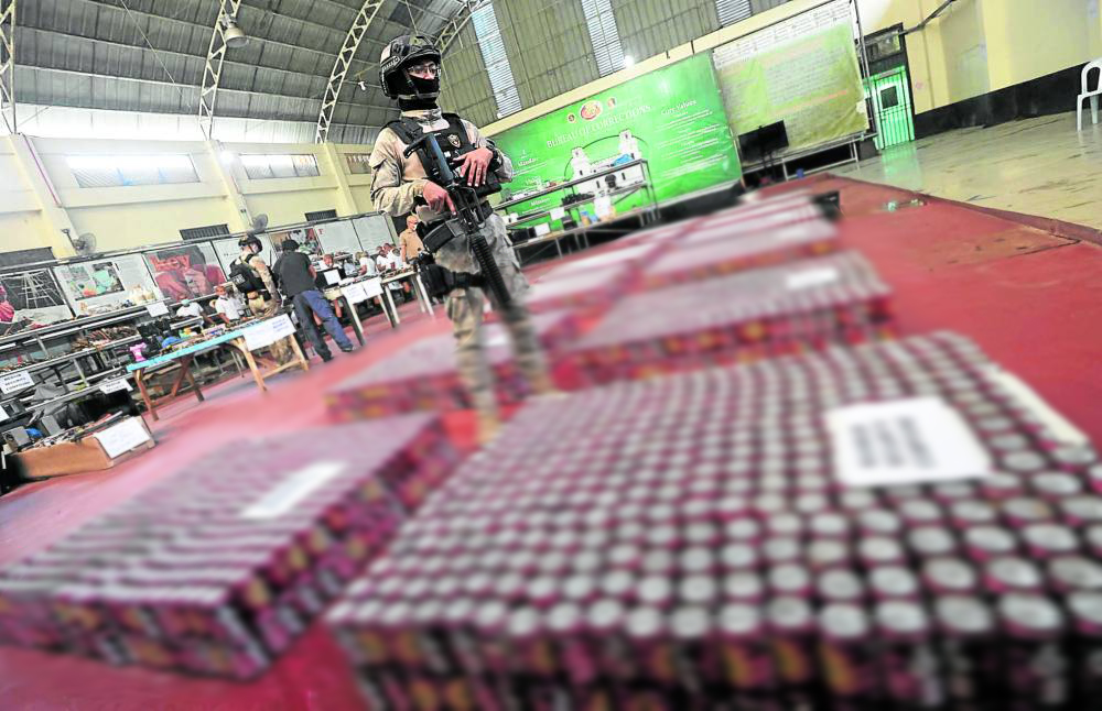 Cop watches over cans of beer seized from the NBP. STORY: Bilibid gangs kept beer to last many Oktoberfests. 