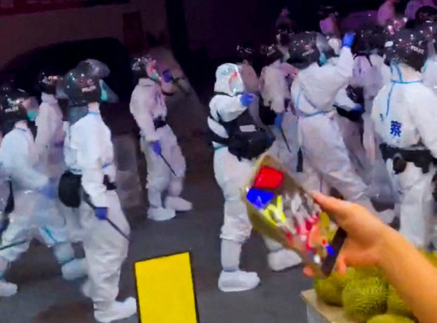 Riot police in personal protection suits (PPE) walk down a street, during protests over coronavirus disease (COVID-19) restrictions, in Guangzhou, Guangdong province, China in this screen grab taken from a social media video released November 29, 2022. Video Obtained by Reuters/via REUTERS