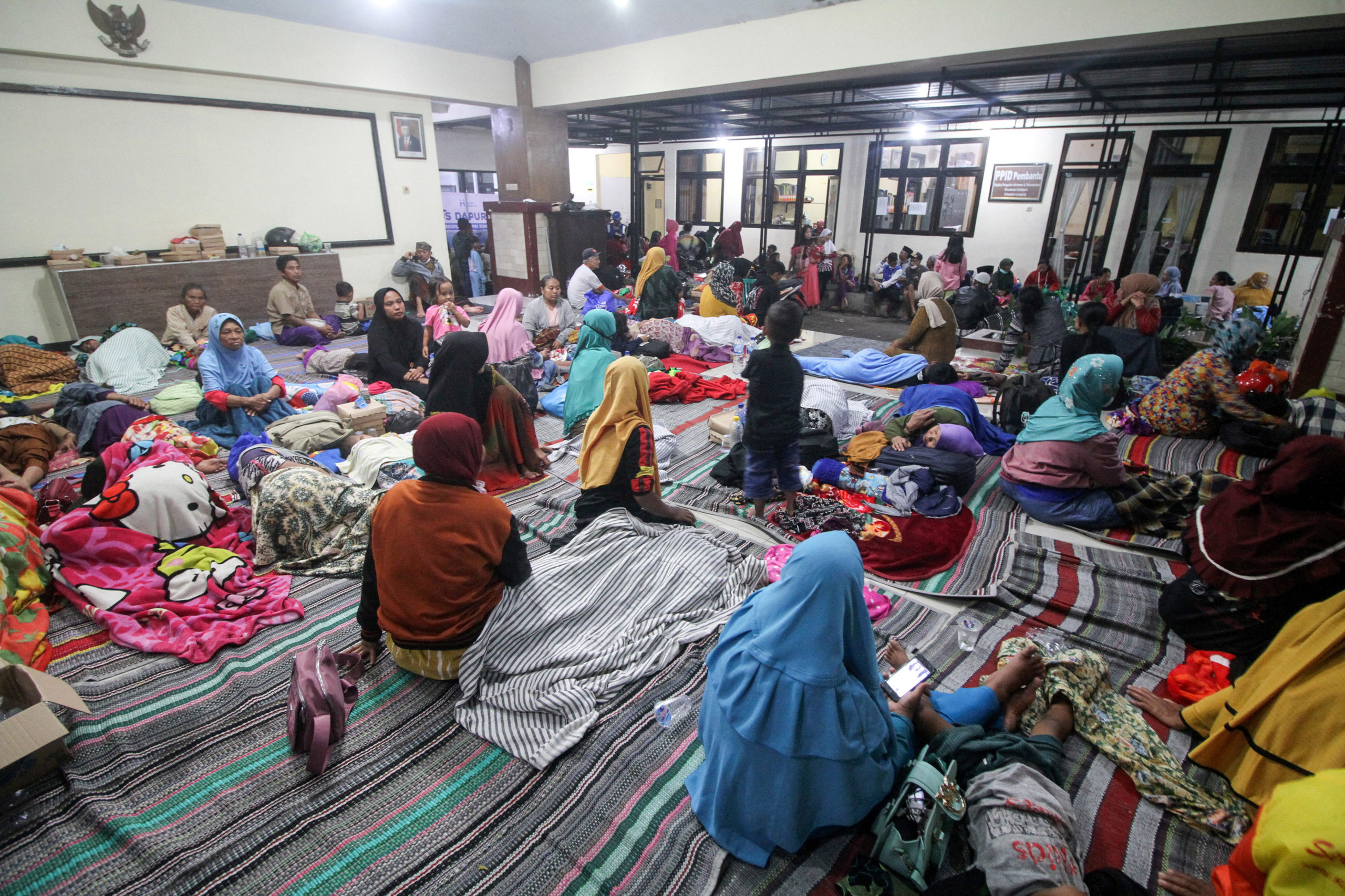 Villagers rest as they shelter at a district office after being evacuated following the eruption of Mount Semeru volcano in Lumajang, East Java province, Indonesia, December 4, 2022, in this photo taken by Antara Foto. Antara Foto/Umarul Faruq/ via REUTERS