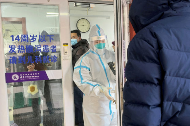 People line up next to a medical worker in a protective suit, at a fever clinic of a hospital amid the coronavirus disease (COVID-19) outbreak in Beijing, China December 15, 2022. REUTERS/Josh Arslan