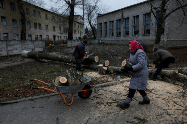Pilaheia Mykhailivna, 73 puts wood she and her neighbours chopped up from cutting down municipal city trees, into a wheelbarrow, to burn for heat, as Russia's attack on Ukraine continues, during intense shelling in Bakhmut, Ukraine, December 26, 2022. REUTERS/Clodagh Kilcoyne