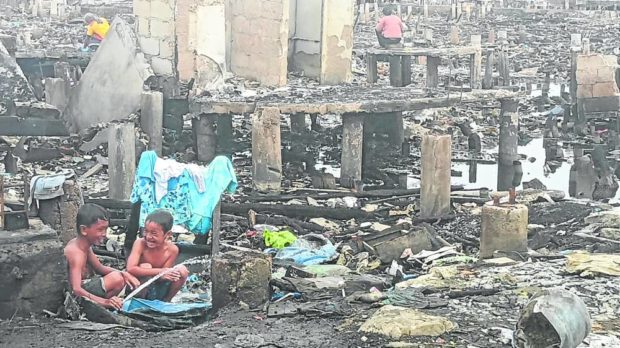 Children, in this photo taken on Dec. 2, play with water from a broken pipe amid the ruins of 250 houses in Sitio Paradise, Barangay Looc, Mandaue City, that were gutted by a fire on Nov. 22. STORY: Senator bats for nationwide inventory of families in danger zones