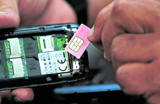 Stock photo, closeup of hands putting a SIM card into a cellphone. STORY: SIM card registration: Things the public must remember