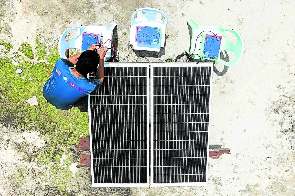 Um professor prepara baterias para conectar aos painéis solares que alimentam as televisões usadas em aulas na Halian Elementary School em uma ilha remota em Del Carmen, Surigao del Norte.