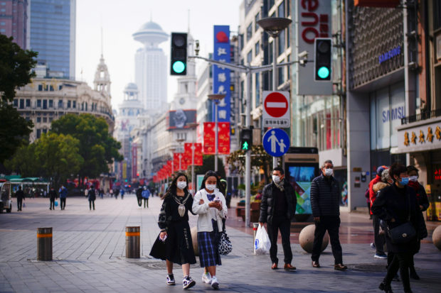 FILE PHOTO: People wearing face masks walk at a main shopping area in Shanghai