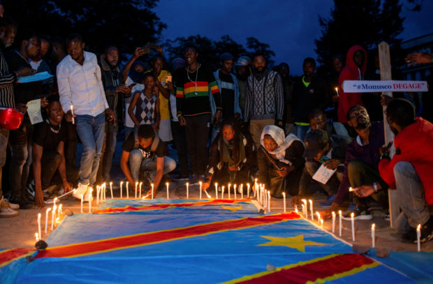 Congolese activists light candles on their national flag during a vigil in memory of the civilians killed in the recent conflict between Armed Forces of the Democratic Republic of the Congo (FARDC) and rebel forces, in Goma, in the North Kivu province of the Democratic Republic of Congo December 5, 2022. REUTERS/Arlette Bashizi