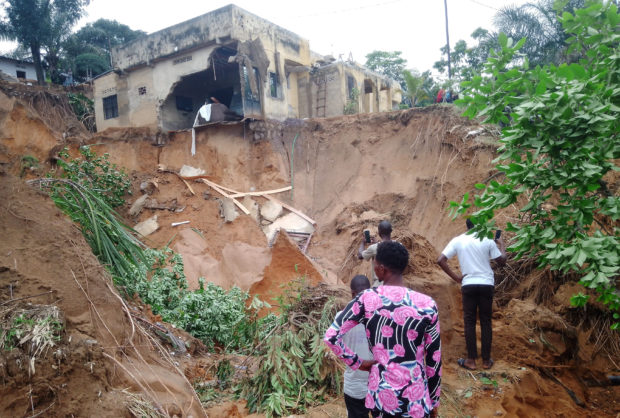 People stand watch after heavy rains caused floods and landslides, on the outskirts of Kinshasa,