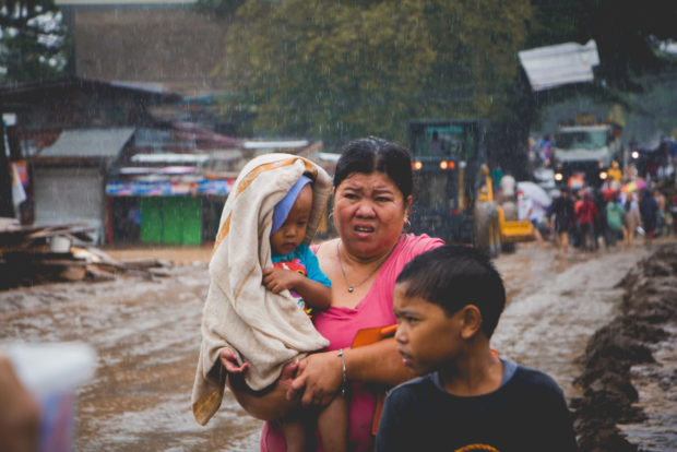A mother takes her children to safety amid a second wave of flooding in a village in Oroquieta City on Monday, Dec. 26, 2022. STORY: Visayas, Mindanao residents affected by flooding get P88 million in aid