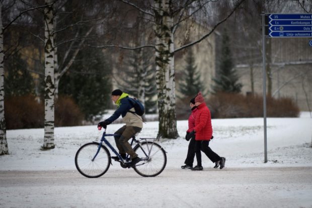 This picture taken on December 1, 2022 in Oulu, Finland shows a man as he rides a bicycle on a snowy cycle track. - Winter's first snowfall and freezing temperatures do not mean the end of the cycling season in the northern Finnish city of Oulu, which brands itself the "capital of winter cycling". (Photo by Olivier MORIN / AFP)