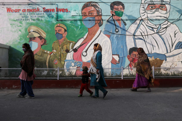 FILE PHOTO: Women walk past a graffiti amidst the spread of the coronavirus disease (COVID-19) in New Delhi