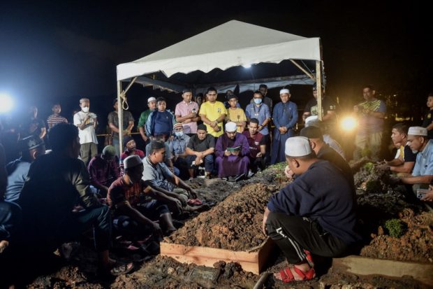 Family members offer prayers for a landslide victim during burial ceremony at Raudhatul Sakinah cemetery in Kuala Lumpur on December 17, 2022. (Photo by Arif Kartono / AFP)