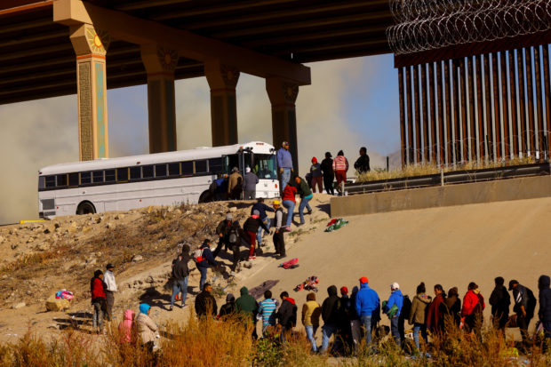 Migrants queue near the border wall after crossing the Rio Bravo river, in Ciudad Juarez