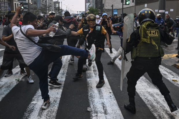 Supporters of Peruvian former President Pedro Castillo clash with riot police during a demonstration demanding his release and the closure of the Peruvian Congress in Lima on December 9, 2022. - Peru's new President Dina Boluarte called for calm on Friday in the wake of violent protests by supporters of former President Pedro Castillo demanding his release and new elections, an alternative she said she did not rule out while announcing the impending formation of his government. (Photo by ERNESTO BENAVIDES / AFP)