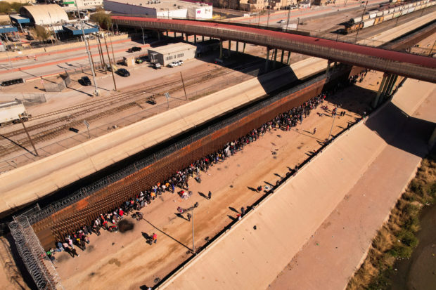 Migrants queue near the border fence after crossing the Rio Bravo river, in Ciudad Juarez