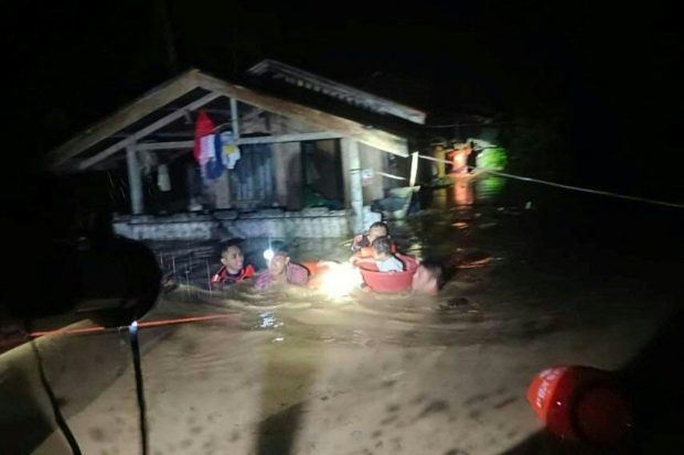 This handout photo taken on December 25, 2022 and received on December 26 from the Philippine Coast Guard shows rescuers evacuating people from a flooded area in Ozamiz City, Misamis Occidental. - Two people were killed and nearly 46,000 others fled their homes as Christmas Day floods dampened the mainly Catholic Philippines's most important holiday, civil defence officials said on December 26. (Photo by Handout / Philippine Coast Guard (PCG) / AFP) / RESTRICTED TO EDITORIAL USE - MANDATORY CREDIT "AFP PHOTO / PHILIPPINE COAST GUARD" - NO MARKETING NO ADVERTISING CAMPAIGNS - DISTRIBUTED AS A SERVICE TO CLIENTS