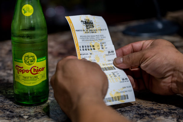 AUSTIN, TEXAS - JANUARY 10: A customer looks over his purchased lottery ticket at a CITGO gas station on January 10, 2023 in Austin, Texas. The Mega Millions jackpot has climbed to $1.1 billion ahead of today's drawing.   Brandon Bell/Getty Images/AFP (Photo by Brandon Bell / GETTY IMAGES NORTH AMERICA / Getty Images via AFP)