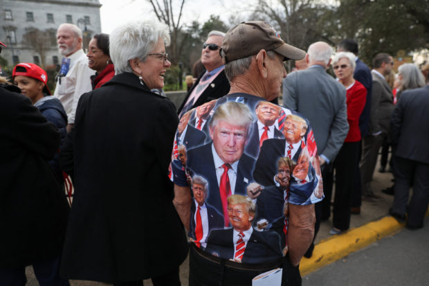 A man wears a T-shirt with images of Former U.S. President Donald Trump on it, on the day of Donald Trump's campaign stop to unveil his leadership team, at the South Carolina State House in Columbia, South Carolina, U.S., January 28, 2023. REUTERS/Shannon Stapleton