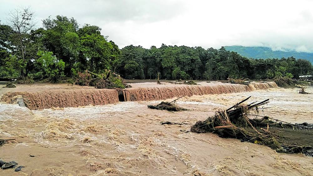 Floodwaters triggered by heavy rains rampage through and damage a spillway at Barangay Mainit in Brooke’s Point, Palawan, on Jan. 5. The cost of damage to the town’s roads and bridges due to the massive flooding reached almost P40 million. 