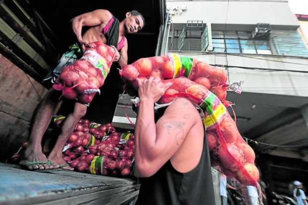THEY’RE HERE Truck helpers unload imported onions so these can be stored in a warehouse in Divisoria, Manila, on Monday. It was not clear if this shipment, labeled as “product of China,” is part of the government’s first batch of onion imports that arrived in the country. —GRIG C. MONTEGRANDE