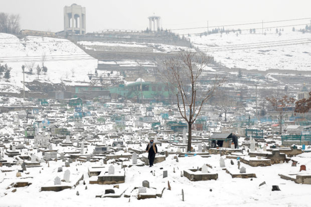 FILE PHOTO: An Afghan man walks on a snow-covered cemetery in Kabul