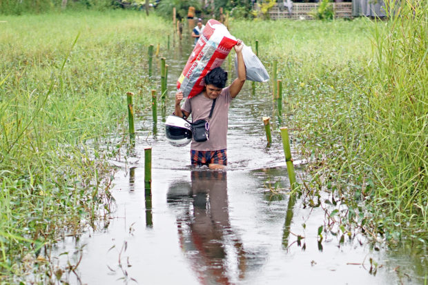 A resident of Barangay Villa Kananga carries his family's belongings, navigating through the flooded waters on Tuesday. Several parts of Butuan City was flooded as a result of heavy rains brought by a low-pressure area on Jan. 10, 2023. STORY: 1,000 people displaced by flooding in Butuan City