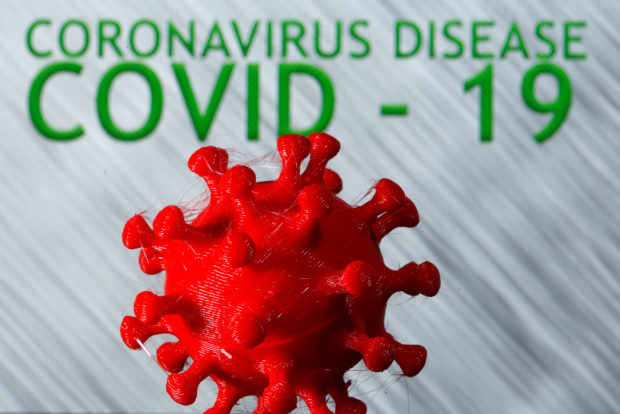 A 3D-printed coronavirus model is seen in front of the words coronavirus disease (Covid-19) on display in this illustration