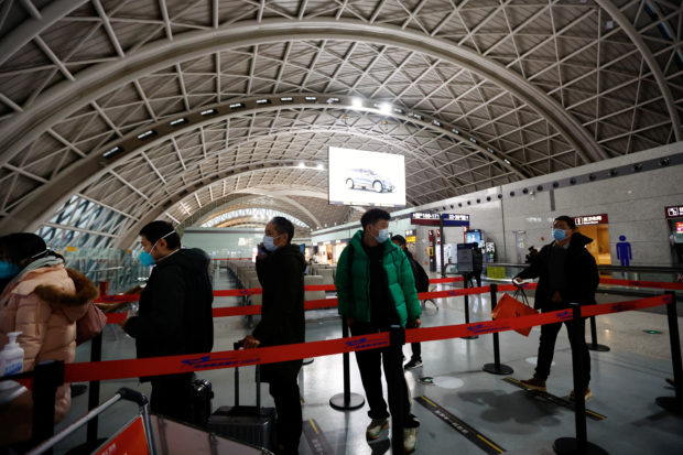 Travellers queue to board a plane at Chengdu Shuangliu International Airport amid a wave of the COVID-19 infections