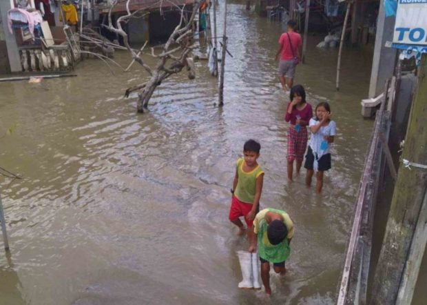 Children walking in a flood in Sapang Bayan in Calumpit, Bulacan. STORY: 