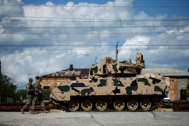FILE PHOTO: U.S. servicemen walk past a Bradley infantry fighting vehicle as they arrive for the joint U.S.-Georgian exercise Noble Partner 2016 in Vaziani