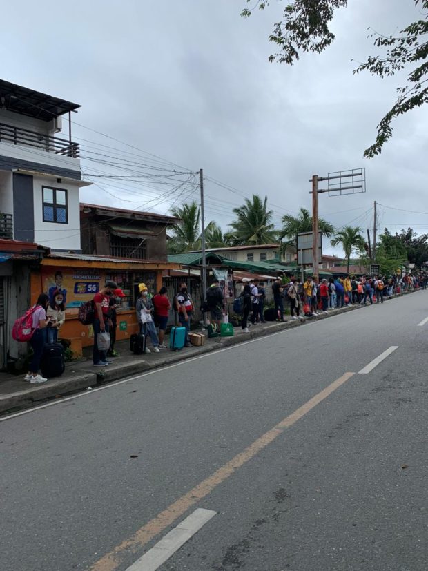 Passengers returning to their hometowns and workplaces wait in a long line at the Calapan City Port