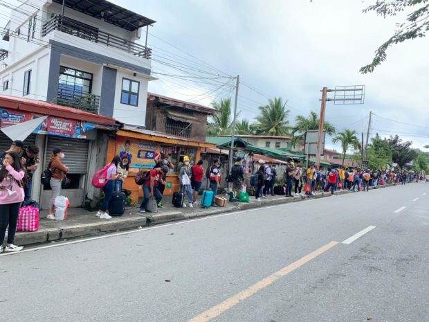 Passengers returning to their hometowns and workplaces wait in a long line at the Calapan City Port