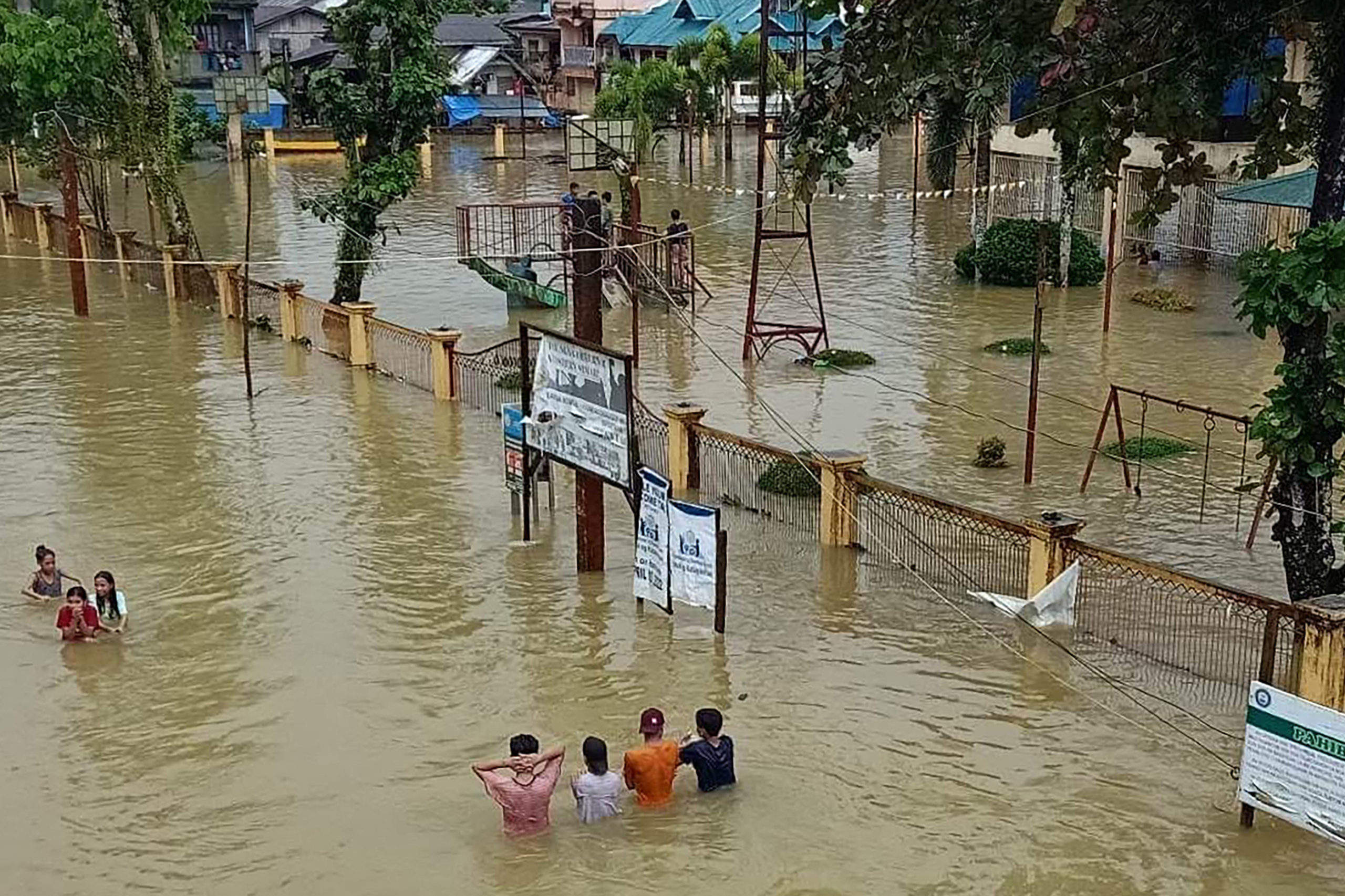 This handout photo taken on January 11, 2023 and received from Jipapad Mayor Benjamin Ver shows residents wading through a flooded road in Jipapad town, Eastern Samar province. At least 11 people have died in storms across the Philippines in the past week, with more heavy rain expected in already sodden regions of the disaster-prone country, authorities said on January 10.