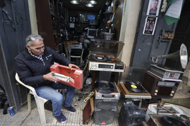 Palestinian Jamal Hemmou checks a portable record player as he sits in front of his shop in the occupied-West Bank city of Nablus, on Jan. 17, 2023. STORY: West Bank vinyl repairman won’t let musical heritage die