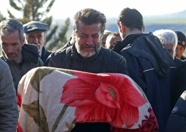 A man carries the body of child who was killed with his parents in a deadly earthquake, during a funeral in the village of Gozebasi in Adiyaman province, Turkey, February 9, 2023. REUTERS/Irakli Gedenidze