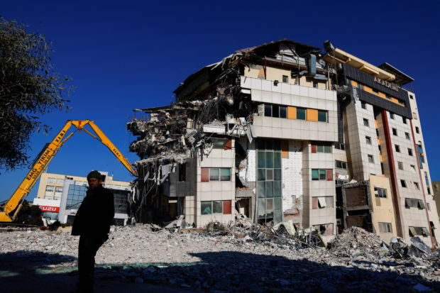 A man stands near an excavator working on the site of a damaged building, in the aftermath of the deadly earthquake, in Hatay, Turkey February 17, 2023. REUTERS/Suhaib Salem